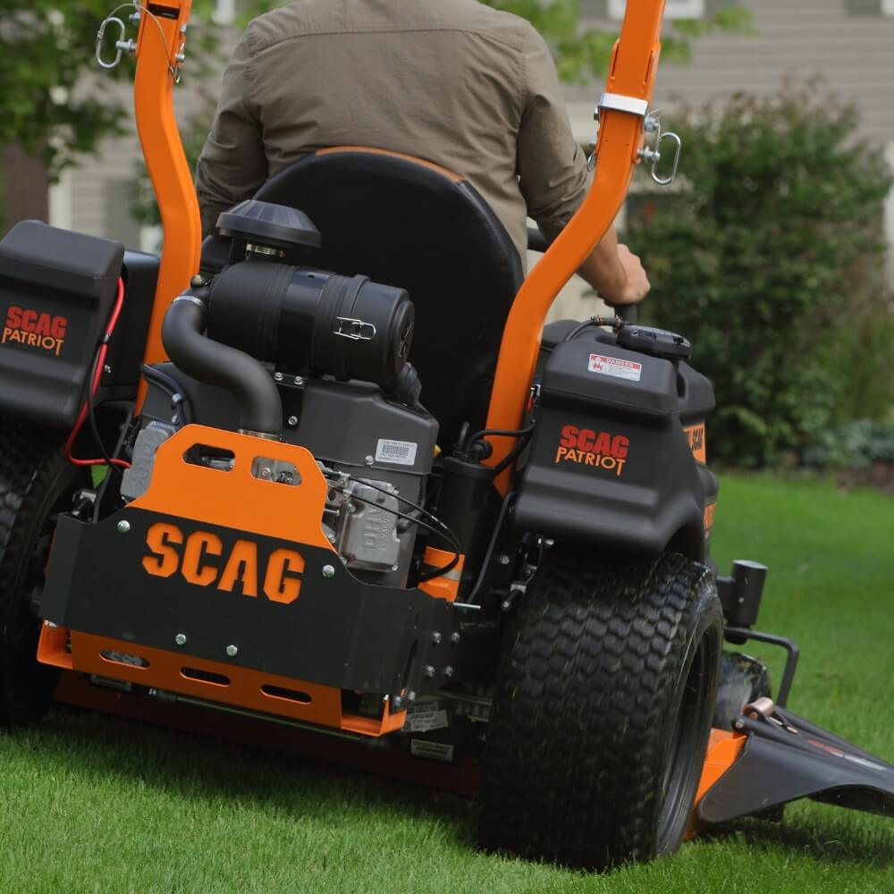 Person operating a SCAG Patriot zero-turn lawn mower on grass