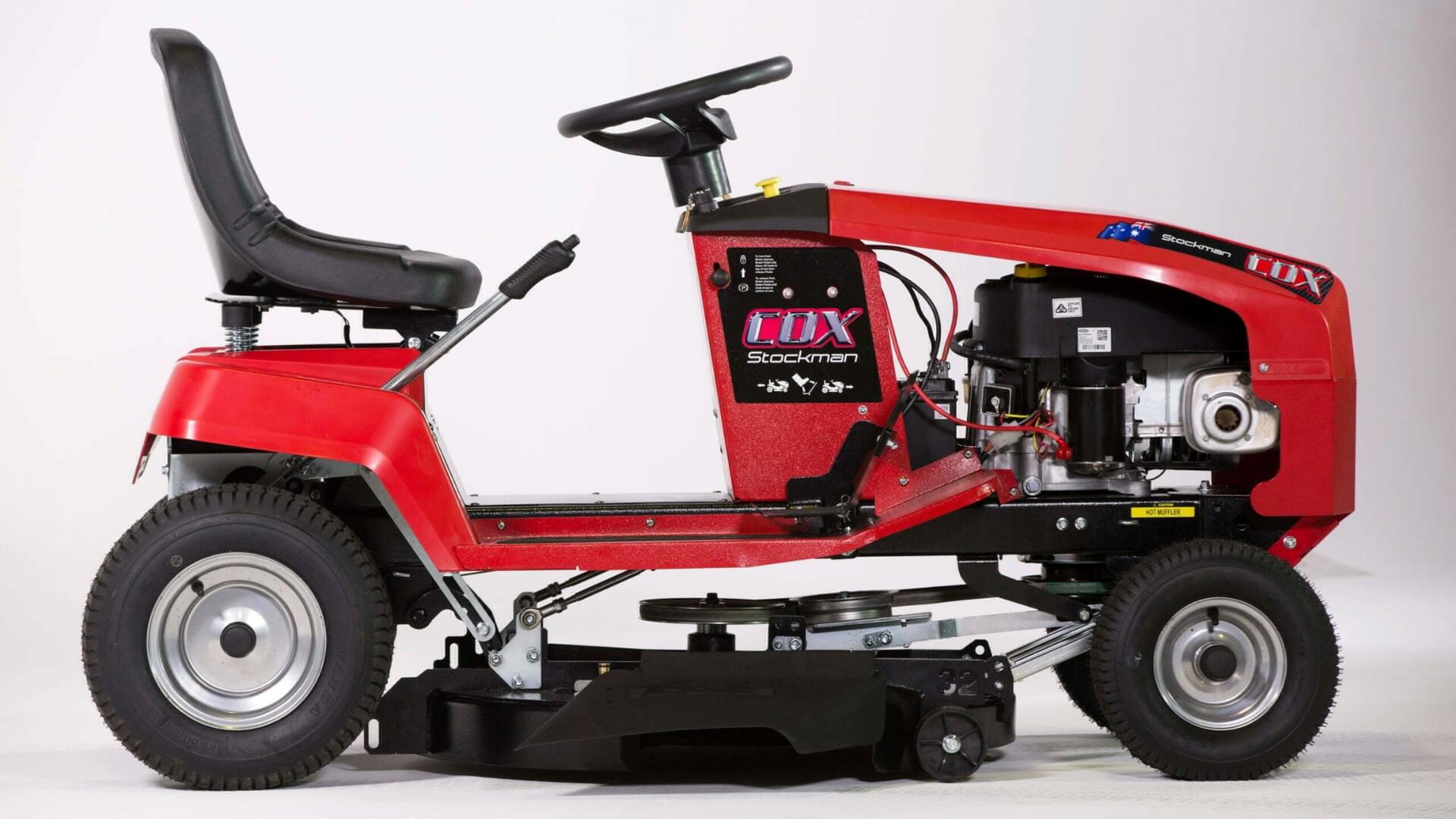 Image showing the side view of the red Cox Stockman ride on mower on a white background.