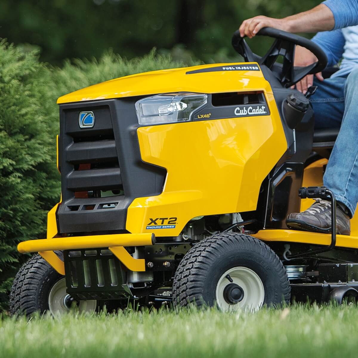 Yellow Cub Cadet XT2 LX42 lawn mower being driven on grass shown from a low angle on the left