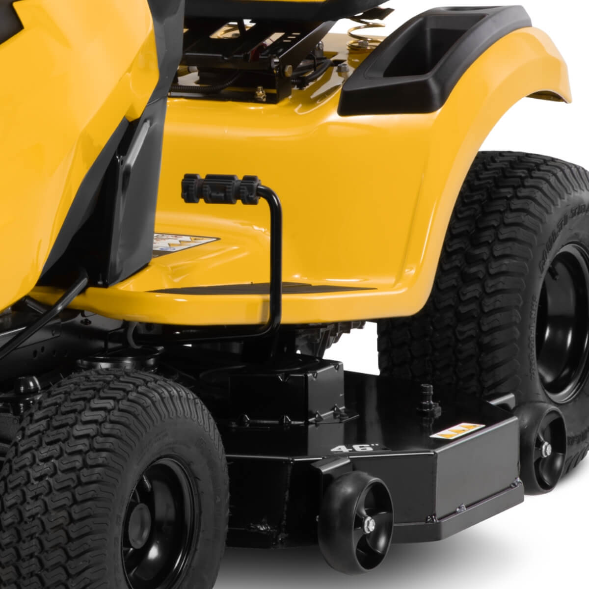 Close-up of a yellow ride on lawn mower with 'Cub Cadet' branding and foot pedal and large tyres with tread with anti scalp wheels.