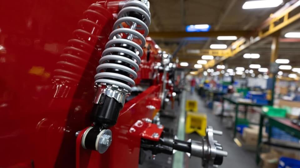 View looking down a factory production line showing a close up of the suspension springs of the Ferris 300 S ride on mower.