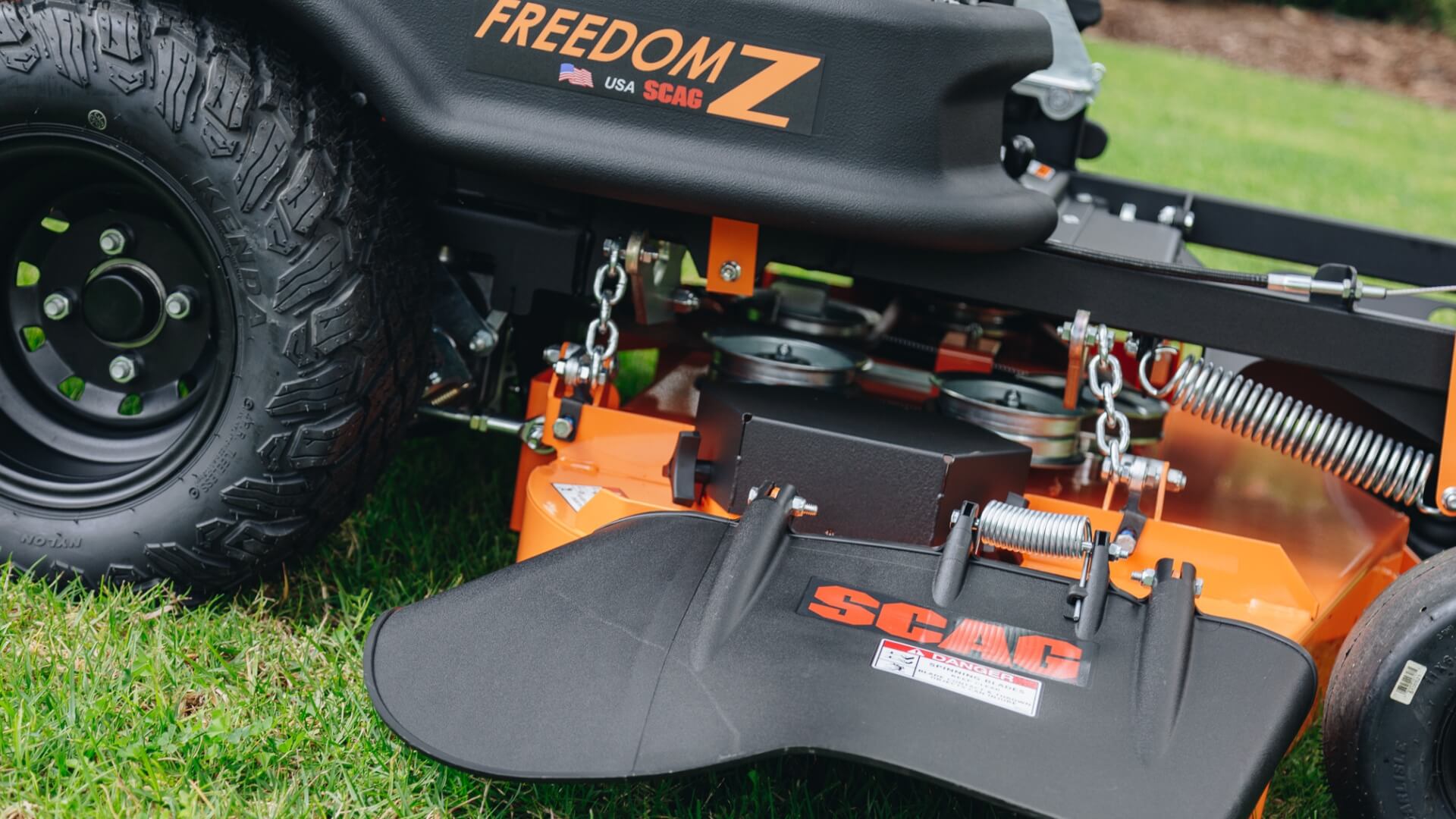 Close view of the side of the SCAG Freedom Z ride on mower with large rear wheel with tread and cutting.deck.