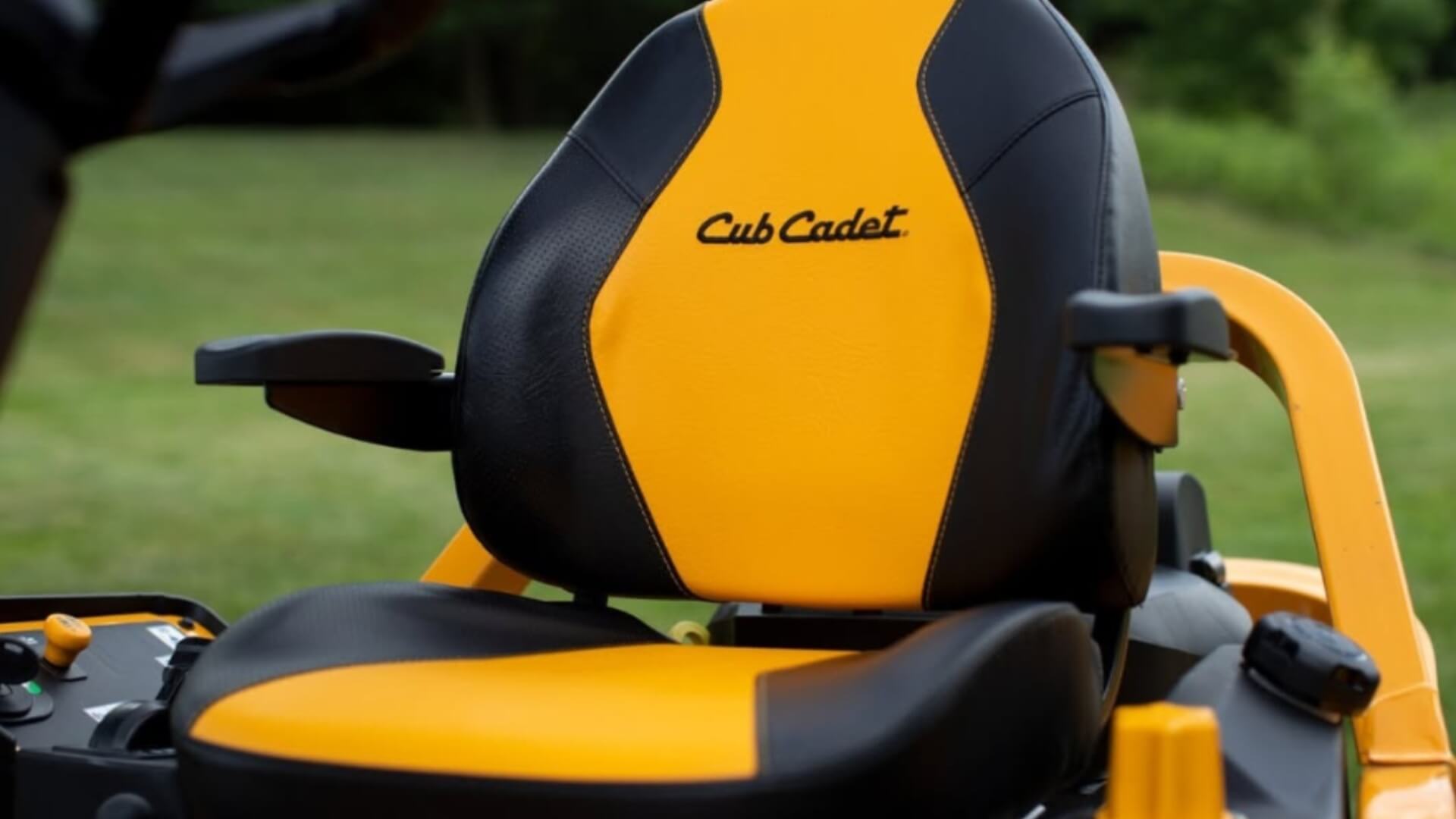 Close-up of a Cub Cadet seat on a lawn mower with a grassy background.