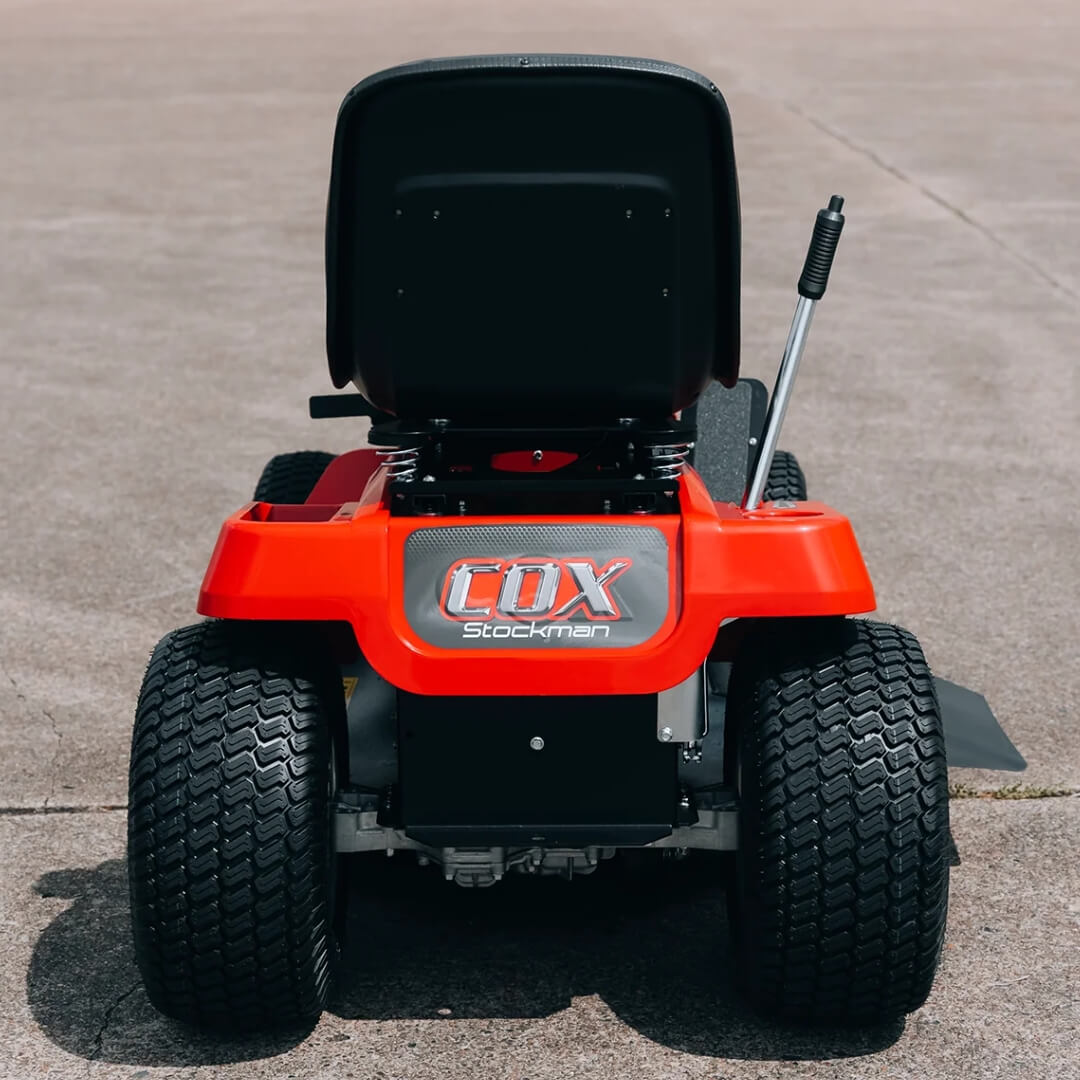 Red lawn mower with 'COX' branding on a concrete surface