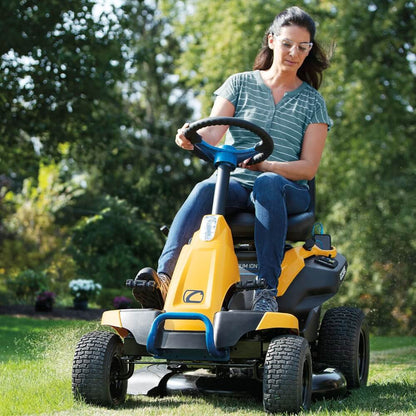 Woman operating a Cub Cadet CC 30E electric powered yellow riding lawn mower in a garden setting