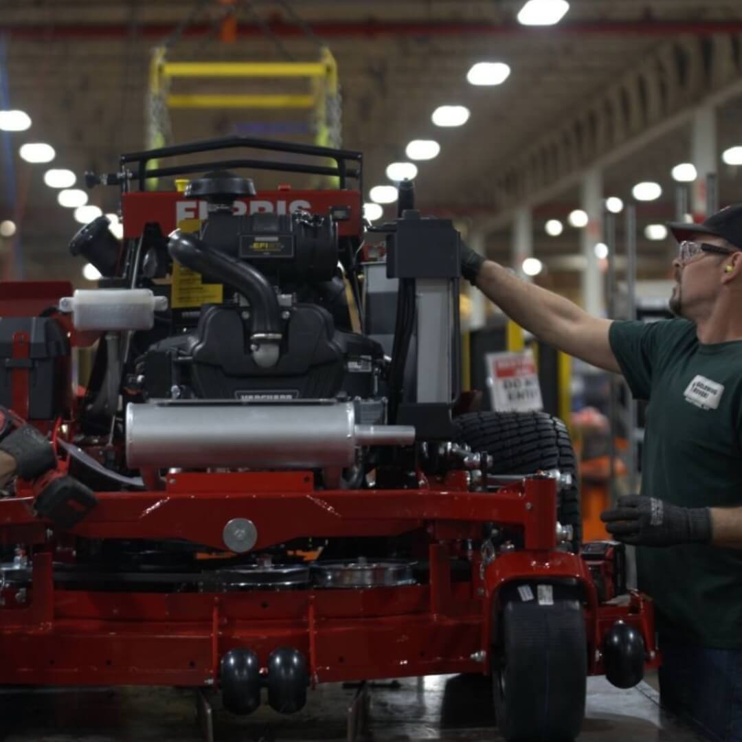 Person working on a large red piece of machinery in a warehouse setting