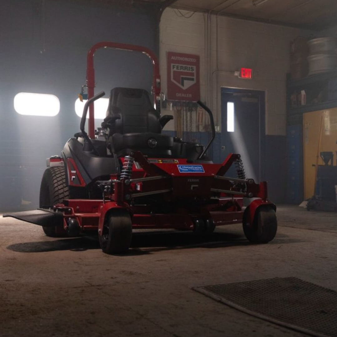 Red riding lawn mower in a garage with visible Ferris logo on a wall.