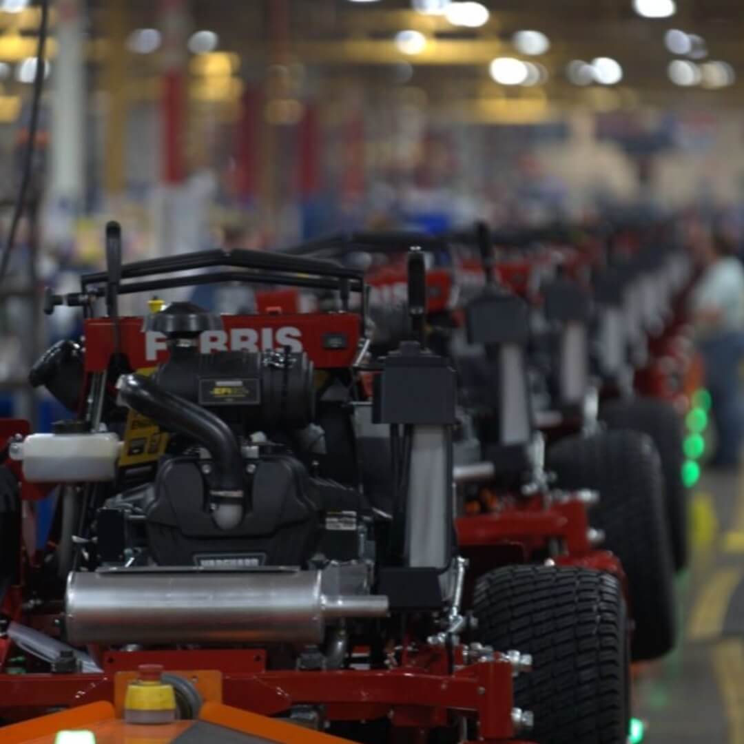 Row of lawn mowers with 'Ferris' branding in a warehouse setting.