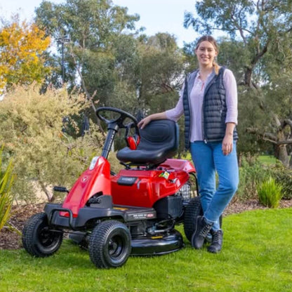 Woman standing next to a red riding lawn mower in a garden setting