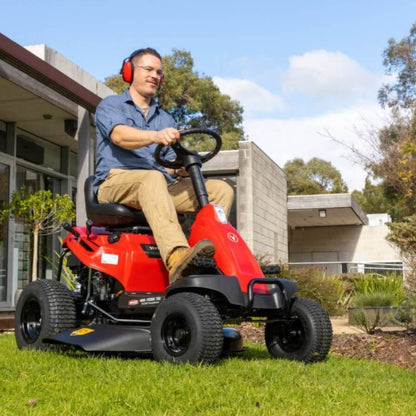 Man operating a red riding lawn mower in a residential area.