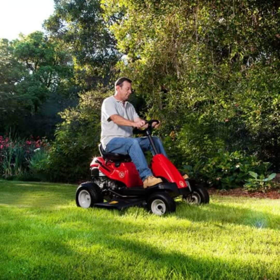 Man operating a red riding lawn mower in a garden setting