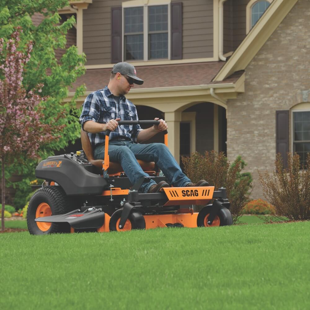 Man operating a SCAG lawn mower in front of a house
