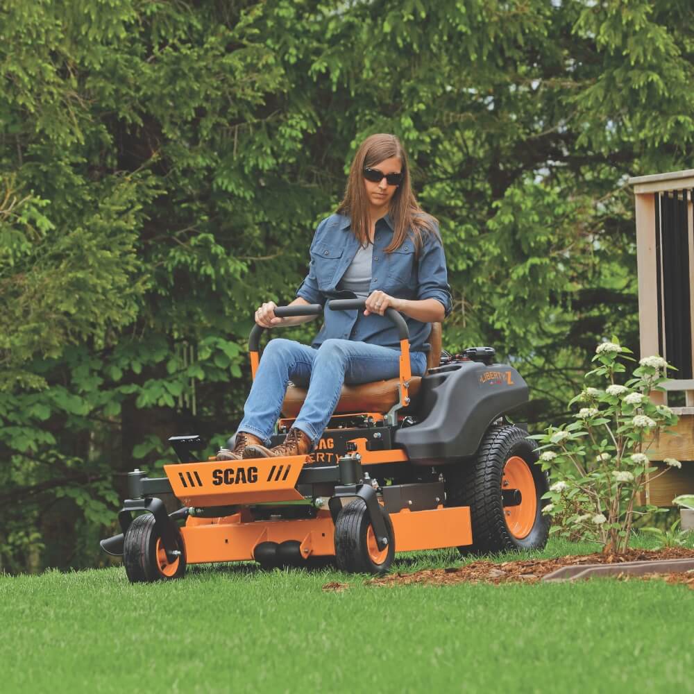 Person operating a SCAG Liberty riding lawn mower in a garden setting