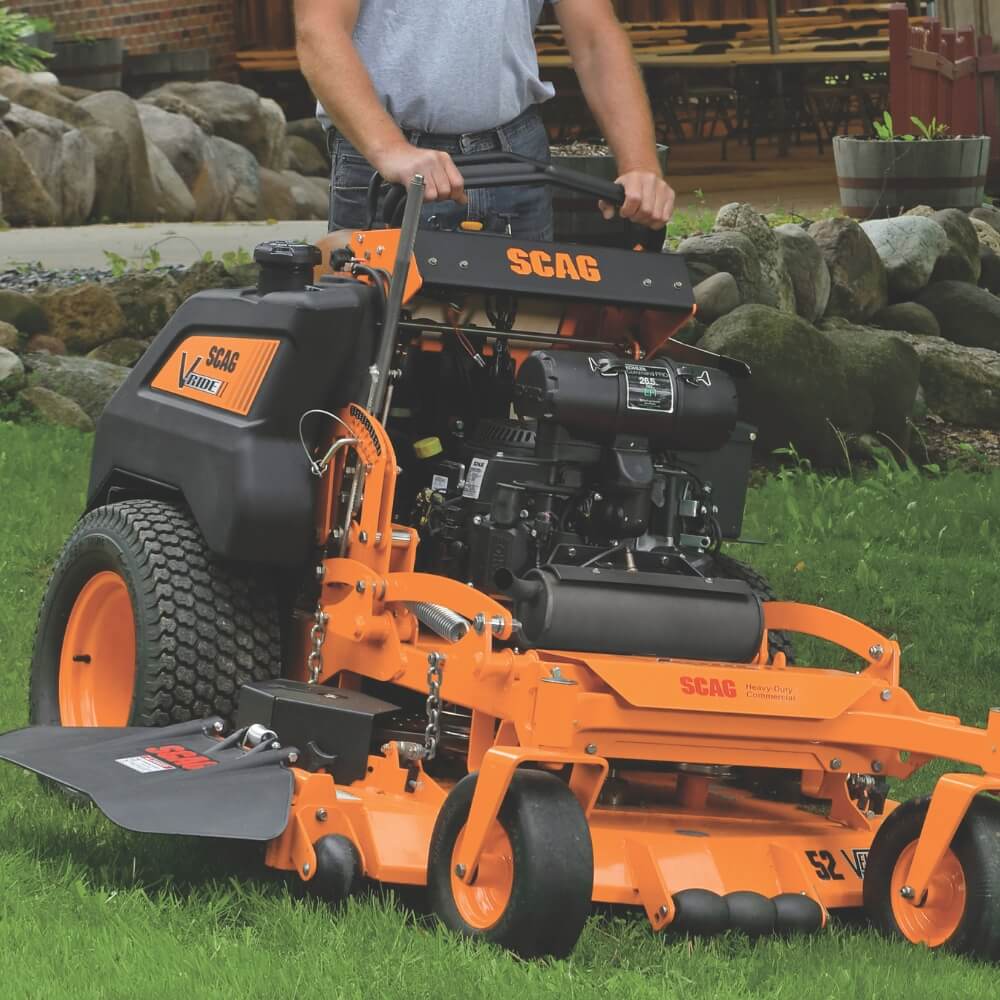 Orange SCAG lawn mower on grass with a person partially visible