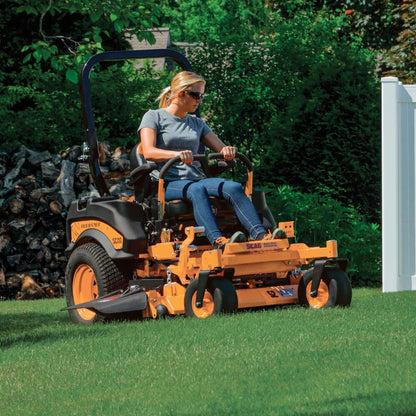 Person operating a yellow riding lawn mower in a garden setting