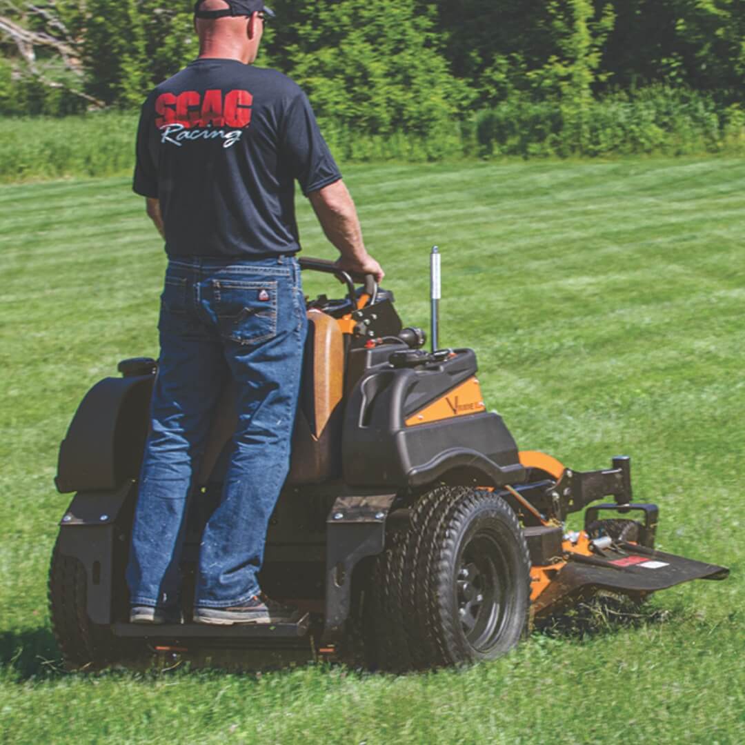 Man operating a SCAG riding lawn mower on a grassy field