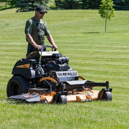 Man standing and operating his mower cutting long green grass.