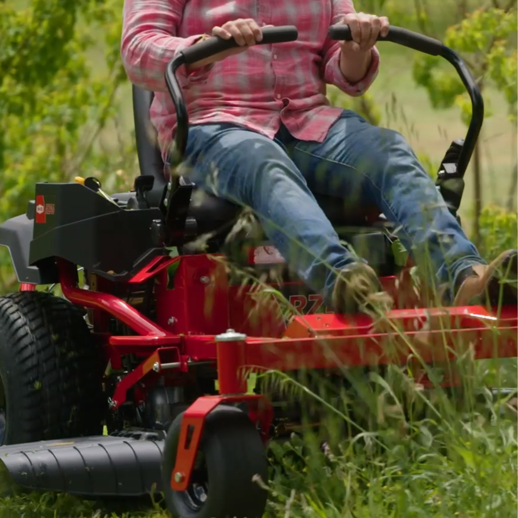 Person operating a red riding lawn mower in a grassy area